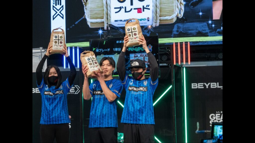 Go for Beyチーム3人で優勝副賞のコメを掲げる様子